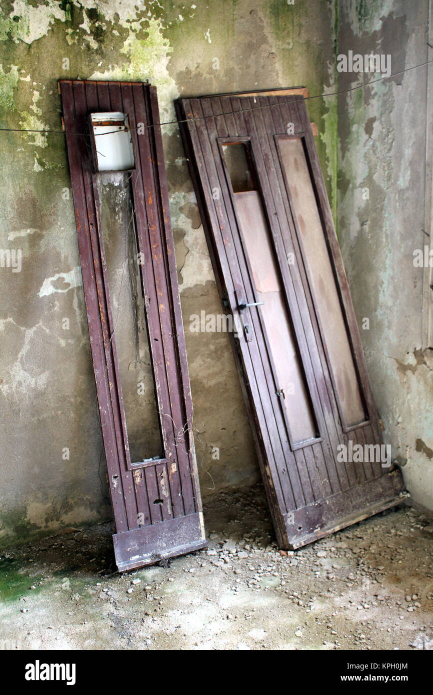 Broken wooden house doors with large glass surface leaned to moldy