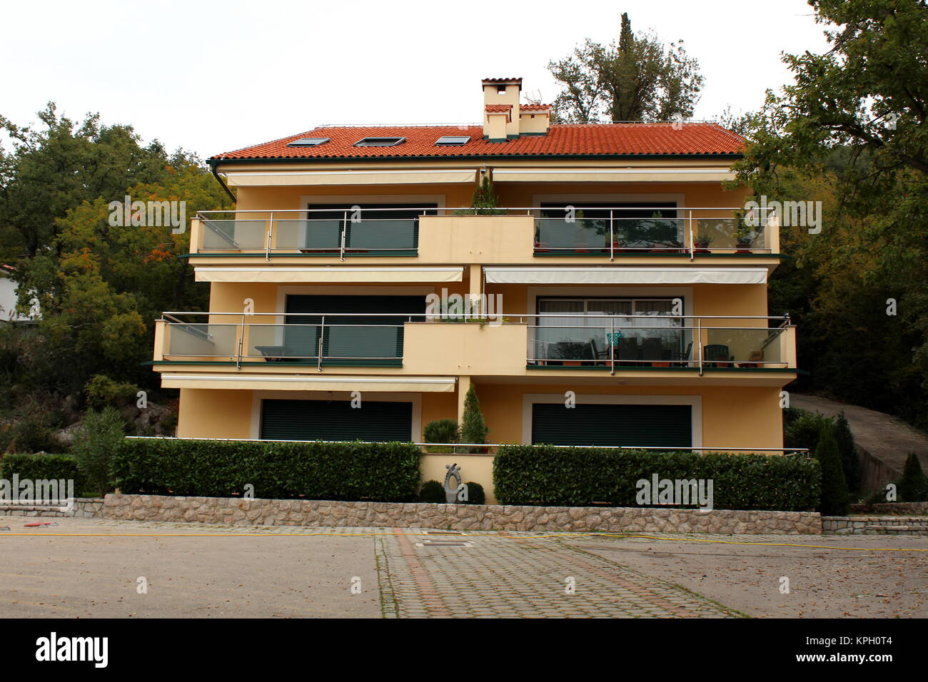 View of Mediterranean villa with four apartments, glass balcony, hedge and ...