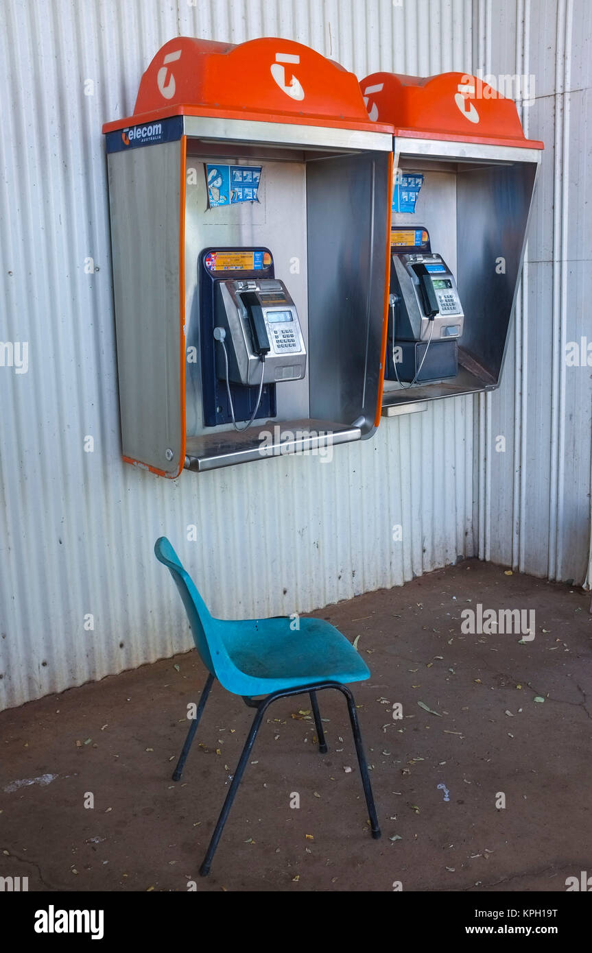 A blue chair in front of two public phone from the Telstra company in the Australian Outback. Telstra is the Australian national phone carrier. Stock Photo