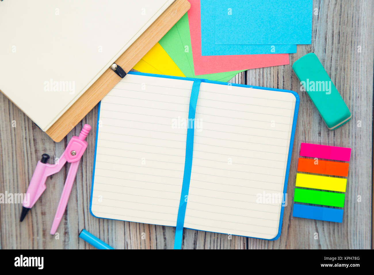 Exams preparation with blank notebooks, a pair of compasses, sticker notes and eraser on a wooden table. Space for your text or product display. Stock Photo