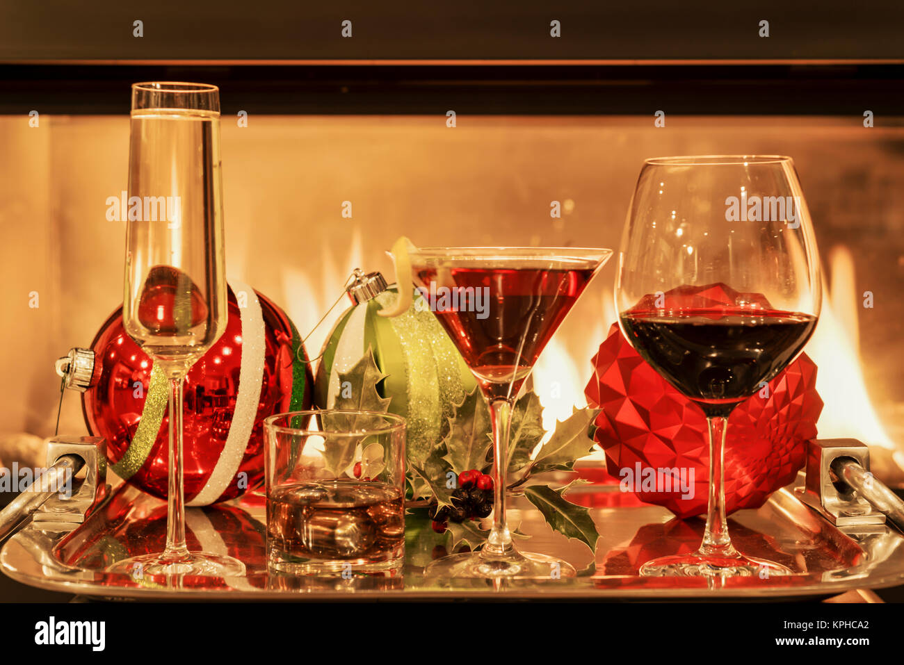 Multiple types of alcoholic drinks with Christmas holiday decorations by a fireplace Stock Photo