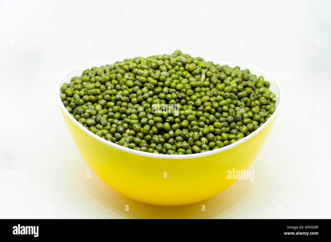 Mung beans in yellow bowl isolated on white background. also known as moong bean, green gram, green bean. its in legume family species Stock Photo