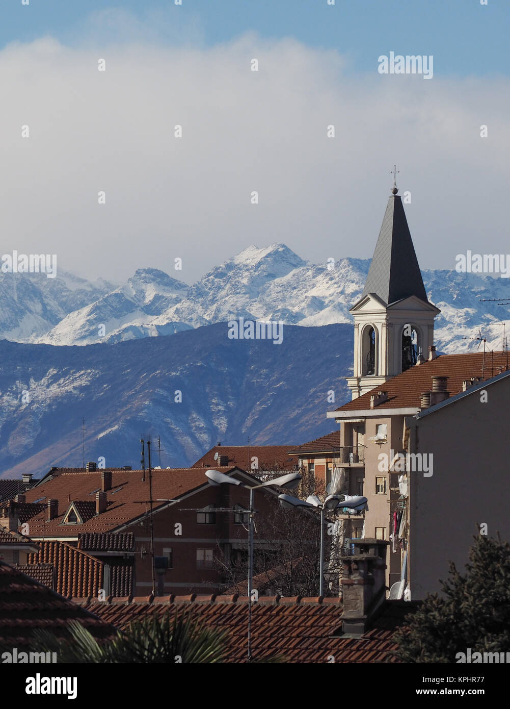 View of the city of Settimo Torinese, Italy with steeple of St Peter in Chains church and the Alps mountains Stock Photo
