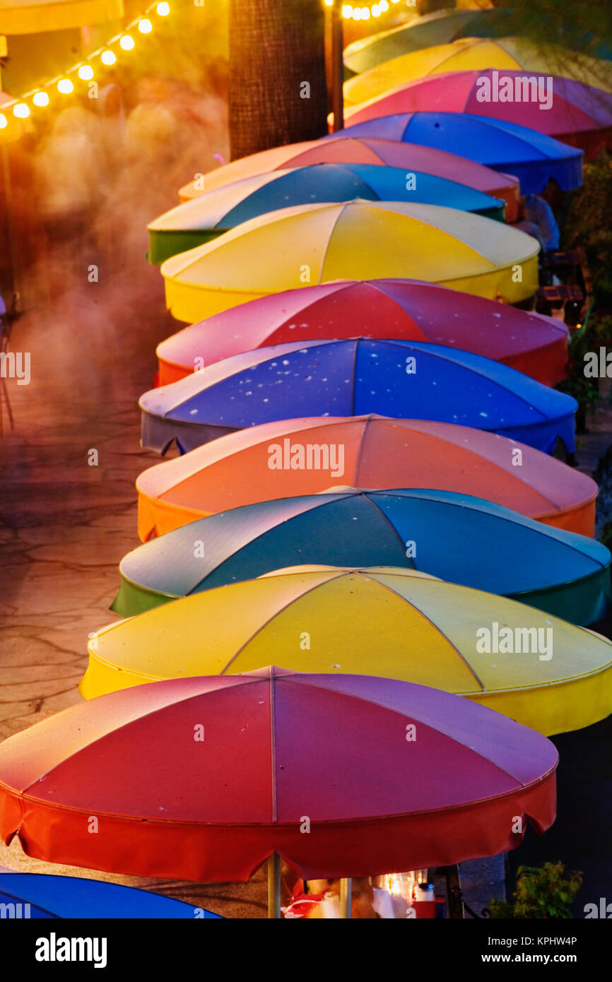 Colorful umbrellas of outdoor cafe and blurred people in motion along famous River Walk and San Antonio River, San Antonio, Texas Stock Photo