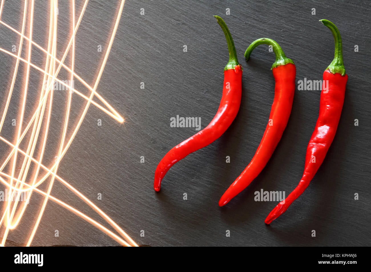 Red chilli peppers laid on a slate serving platter with torch light painted trails Stock Photo