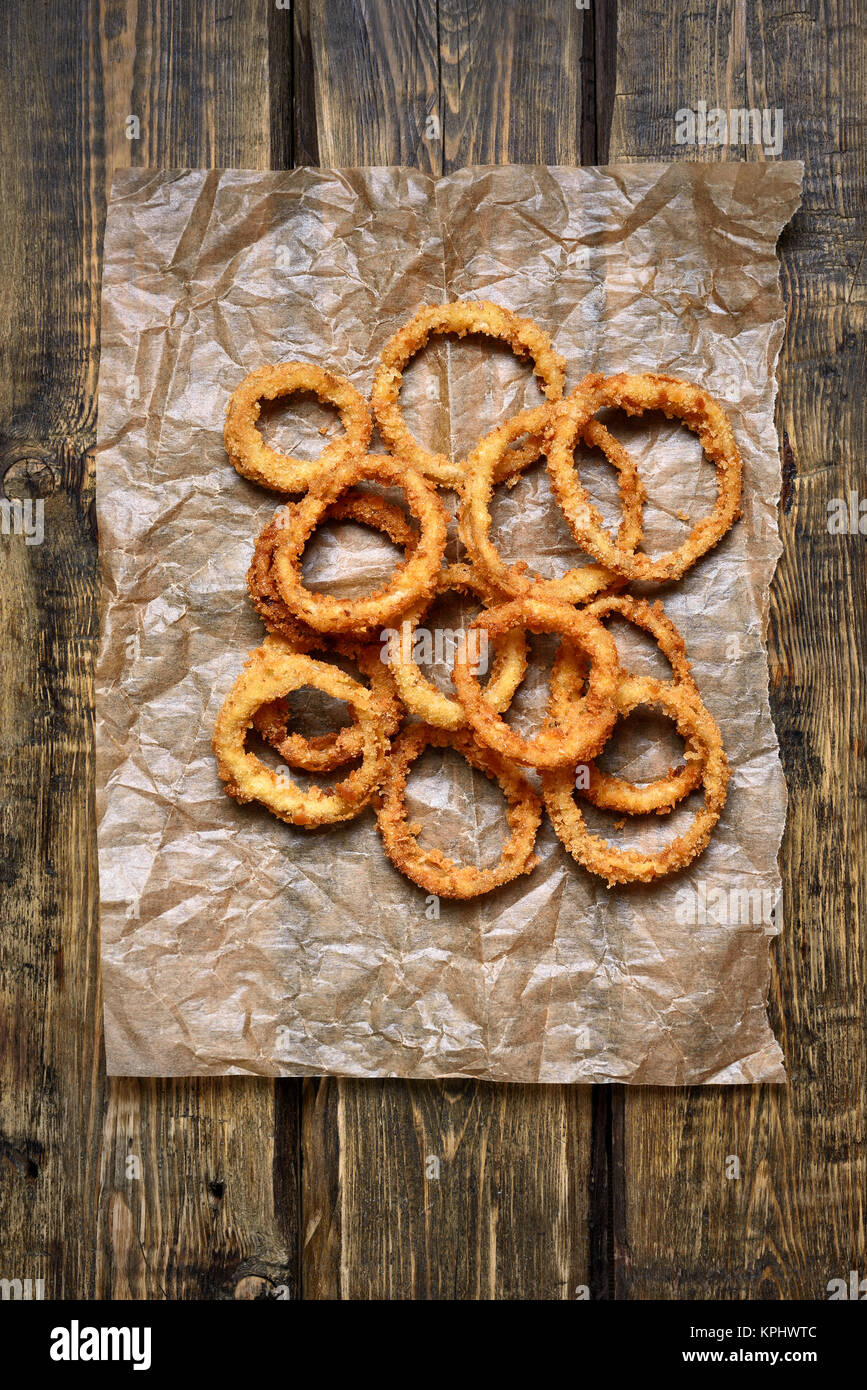 Onion Rings Paper Crispy onion rings on paper over wooden background. Top view, flat lay ...