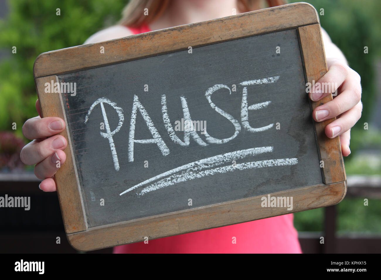 PAUSE (break in German) written with chalk on slate shown by young female Stock Photo