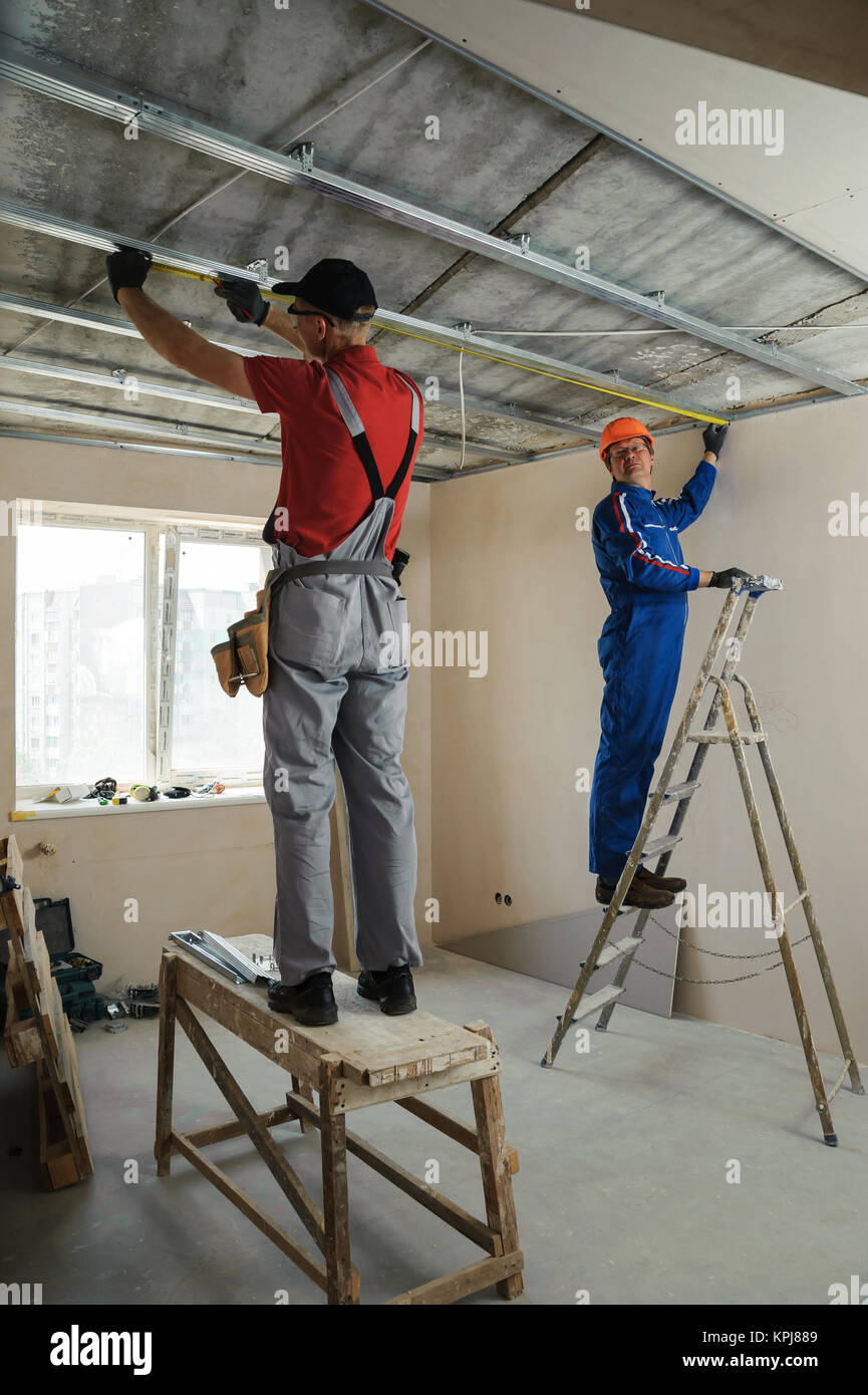 Workers Measure Metal Frame For Plasterboard Ceilings Stock Photo