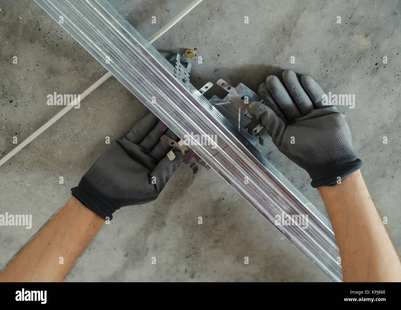 Worker assembles profile metal frame for plasterboard ceilings Stock