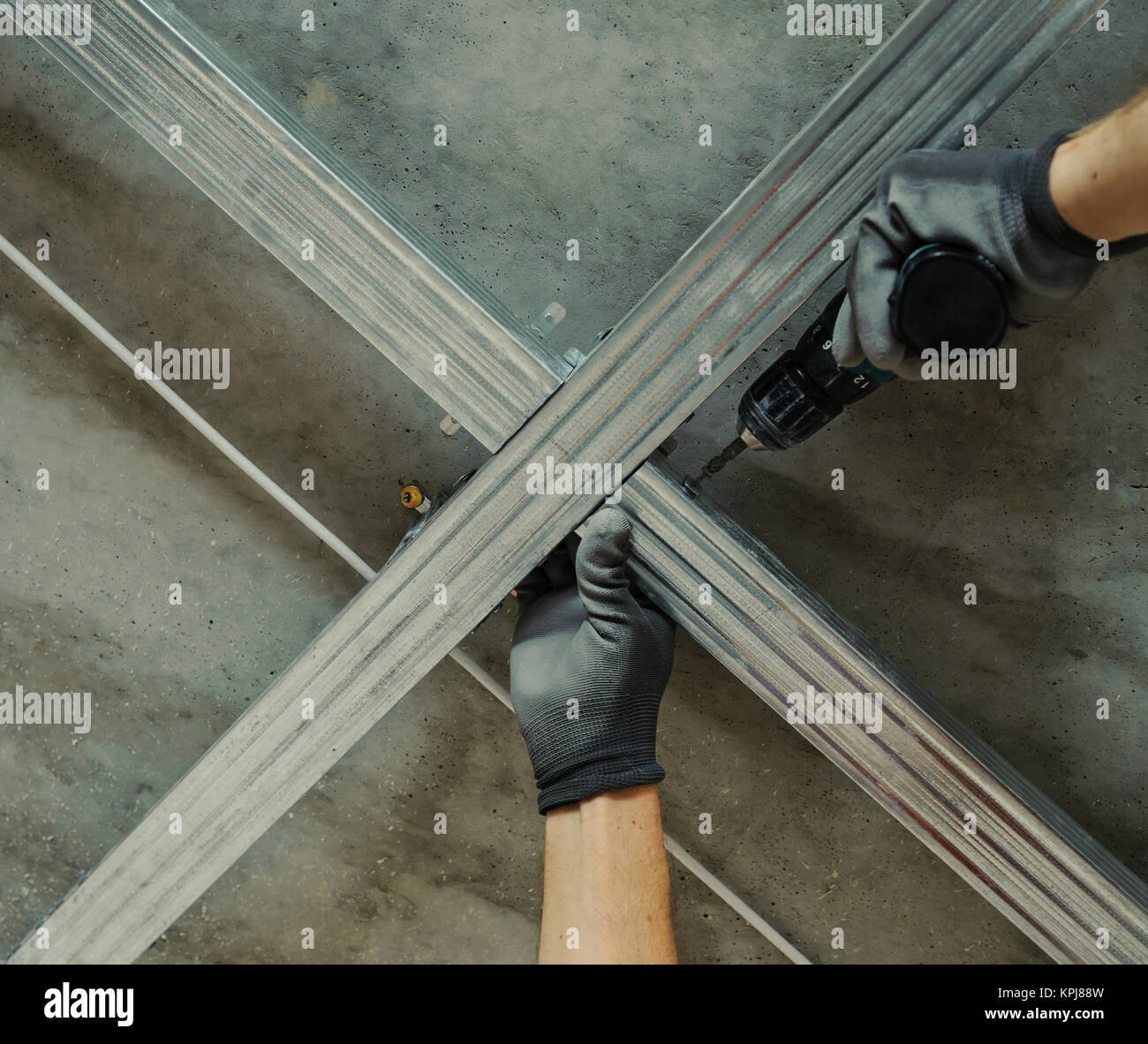 Man assembles profile metal frame for plasterboard ceilings Stock Photo