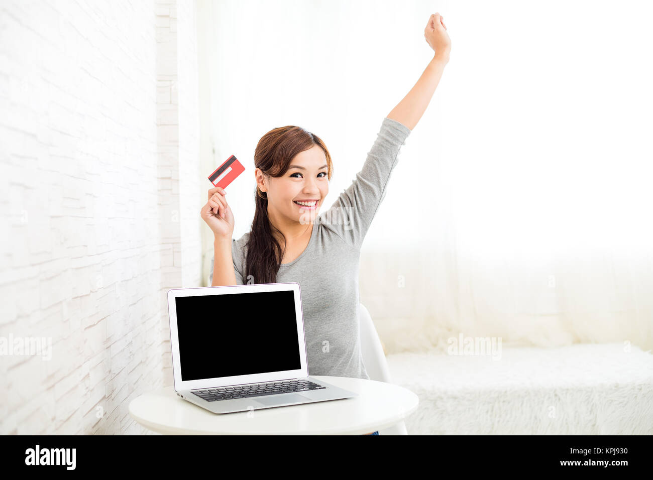 Excited woman holding credit card for online shopping on laptop computer Stock Photo