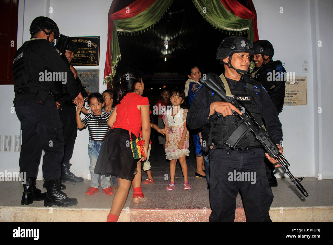 Lhokseumawe, Aceh, Indonesia. 16th Dec, 2017. Several children walk through the policemen agents while heading to the praying room inside the church. Indonesian police conduct routine patrols to prevent anti-terror threats at Lhokseumawe City Church in Aceh. The Indonesian National Police has announced the security and comfort readiness for Christians during the process of celebrating Christmas and welcoming the 2018 new year in Indonesia. Credit: SOPA/ZUMA Wire/Alamy Live News Stock Photo