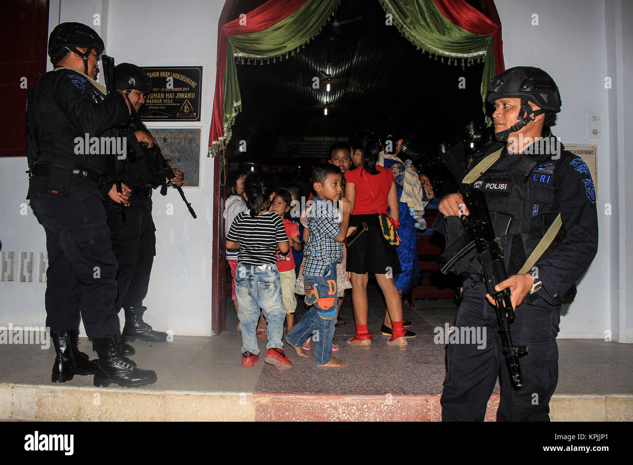 Lhokseumawe, Aceh, Indonesia. 16th Dec, 2017. Several children walk through the policemen agents while heading to the praying room inside the church. Indonesian police conduct routine patrols to prevent anti-terror threats at Lhokseumawe City Church in Aceh. The Indonesian National Police has announced the security and comfort readiness for Christians during the process of celebrating Christmas and welcoming the 2018 new year in Indonesia. Credit: SOPA/ZUMA Wire/Alamy Live News Stock Photo