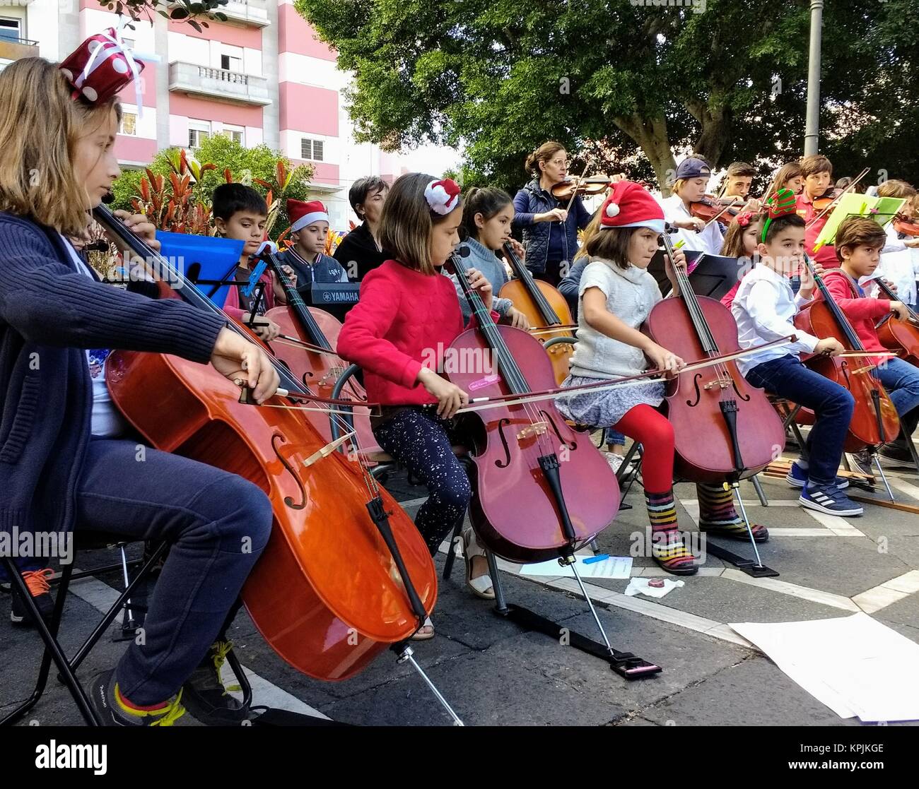 Schoolchildren with Santa Claus hats sit in rows playing Christmas carols on cellos and violins in Weyler Square,,Sta Cruz de Tenerife, Canary Islands Stock Photo