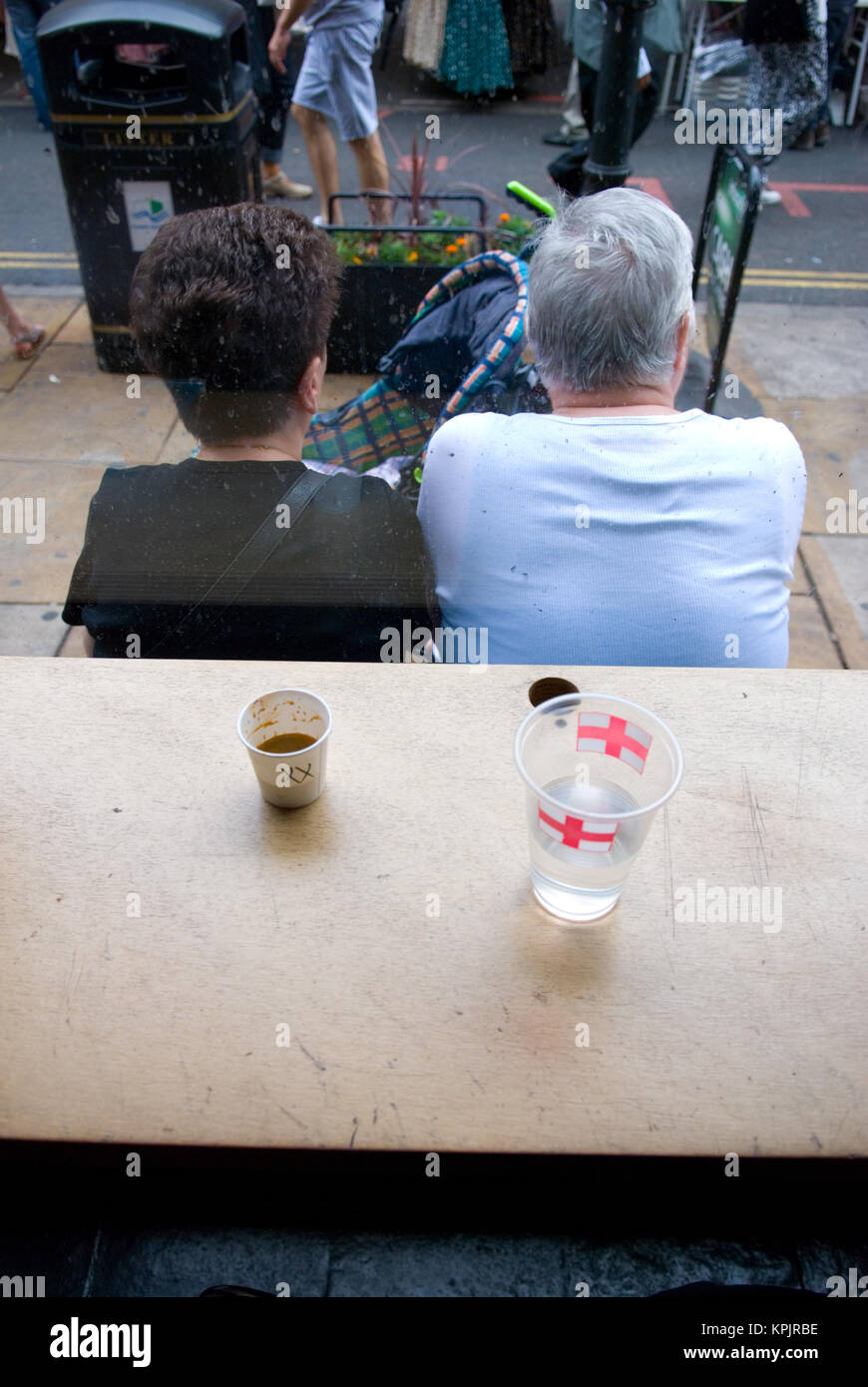 rear view of an elderly couple sitting outside a cafe with two cups on the window sill Stock Photo