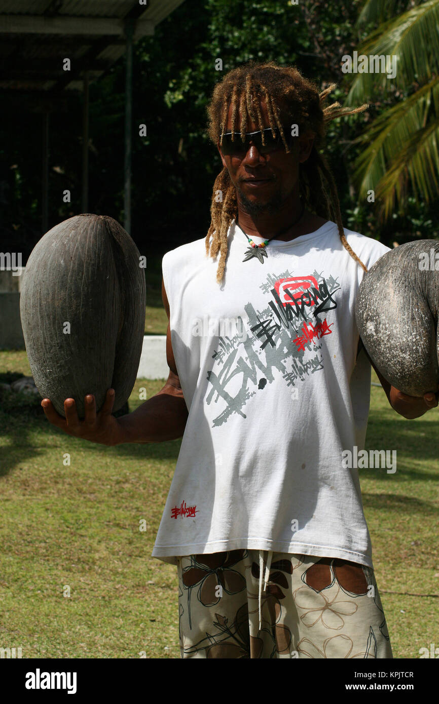 Rastafarian man holding two Coco de Mer fruits in each hand, Curieuse Island, Seychelles. Stock Photo