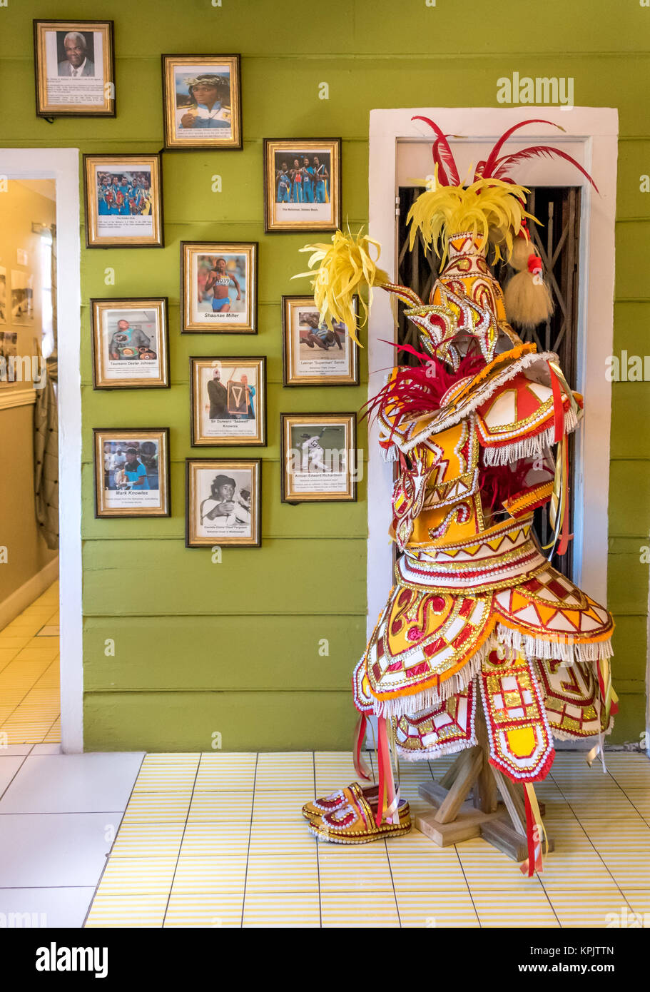 The Heritage Museum of the Bahamas, a colorful yellow Junkanoo costume on display beside photos of important visitors to Graycliff estate in Nassau Stock Photo