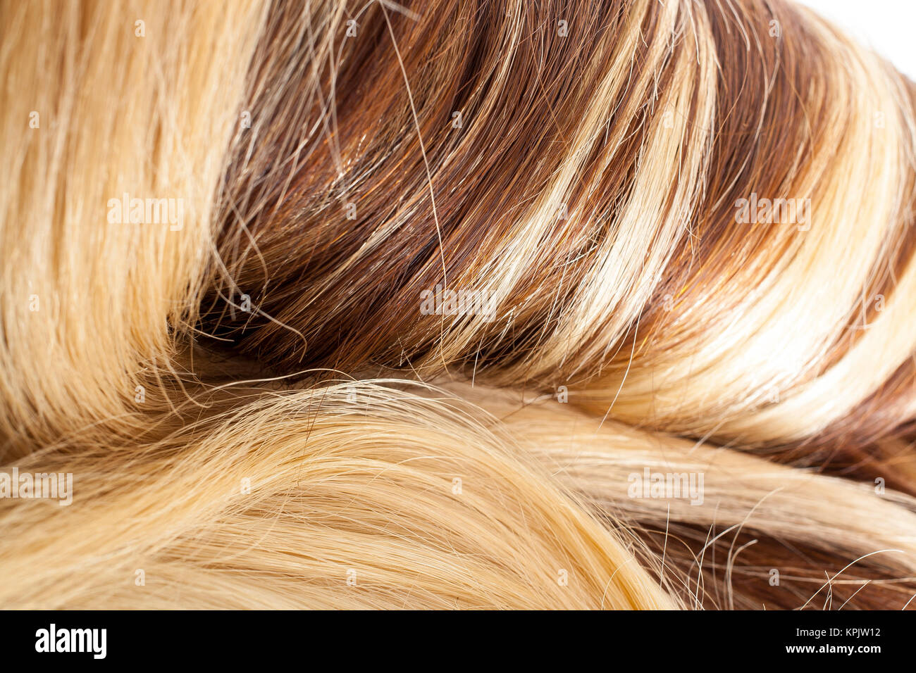 Human hair european hair weft for hair extension. Brown blonde hair texture closeup pattern. Shiny real dyed tail. Stock Photo