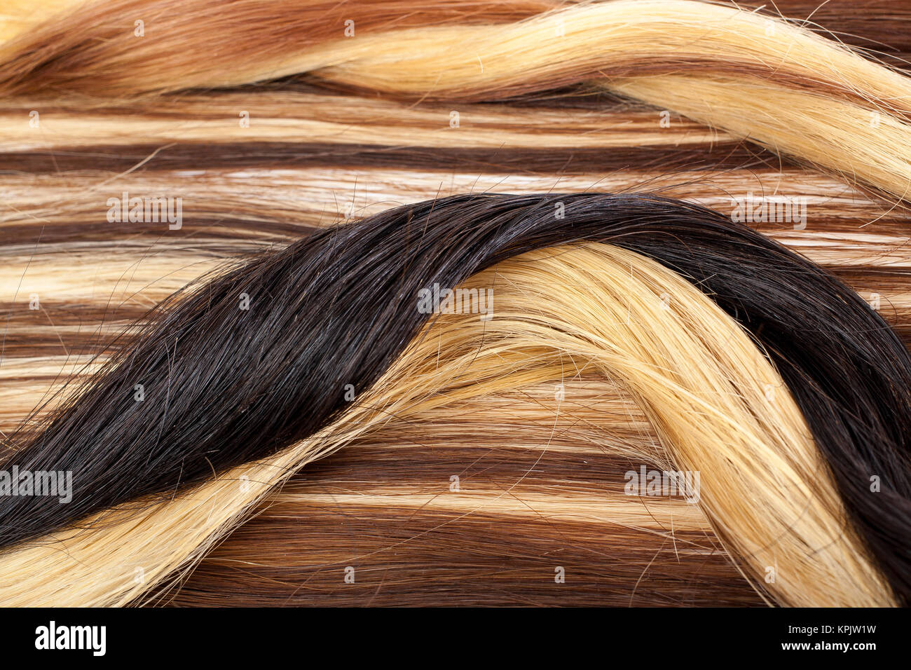 Human hair european hair weft for hair extension. Brown blonde hair texture closeup pattern. Shiny real dyed tail. Stock Photo