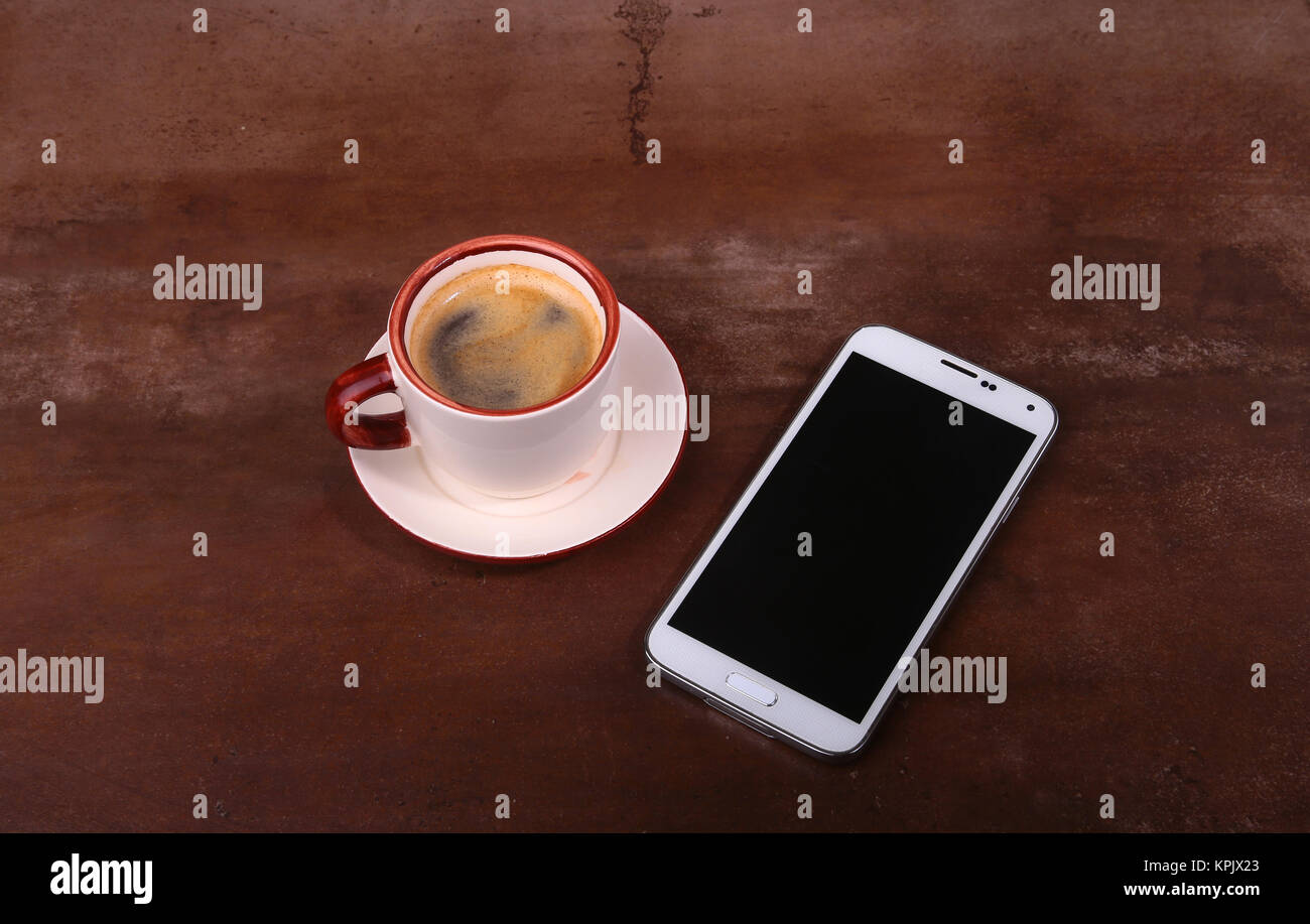 Coffee cup and smartphone on wooden table. View from above Stock Photo