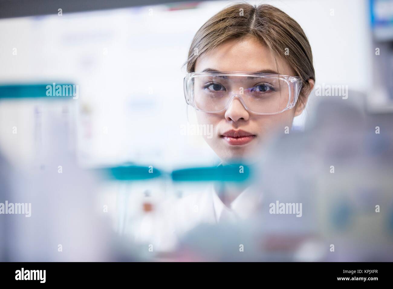 Female laboratory assistant wearing safety goggles. Stock Photo