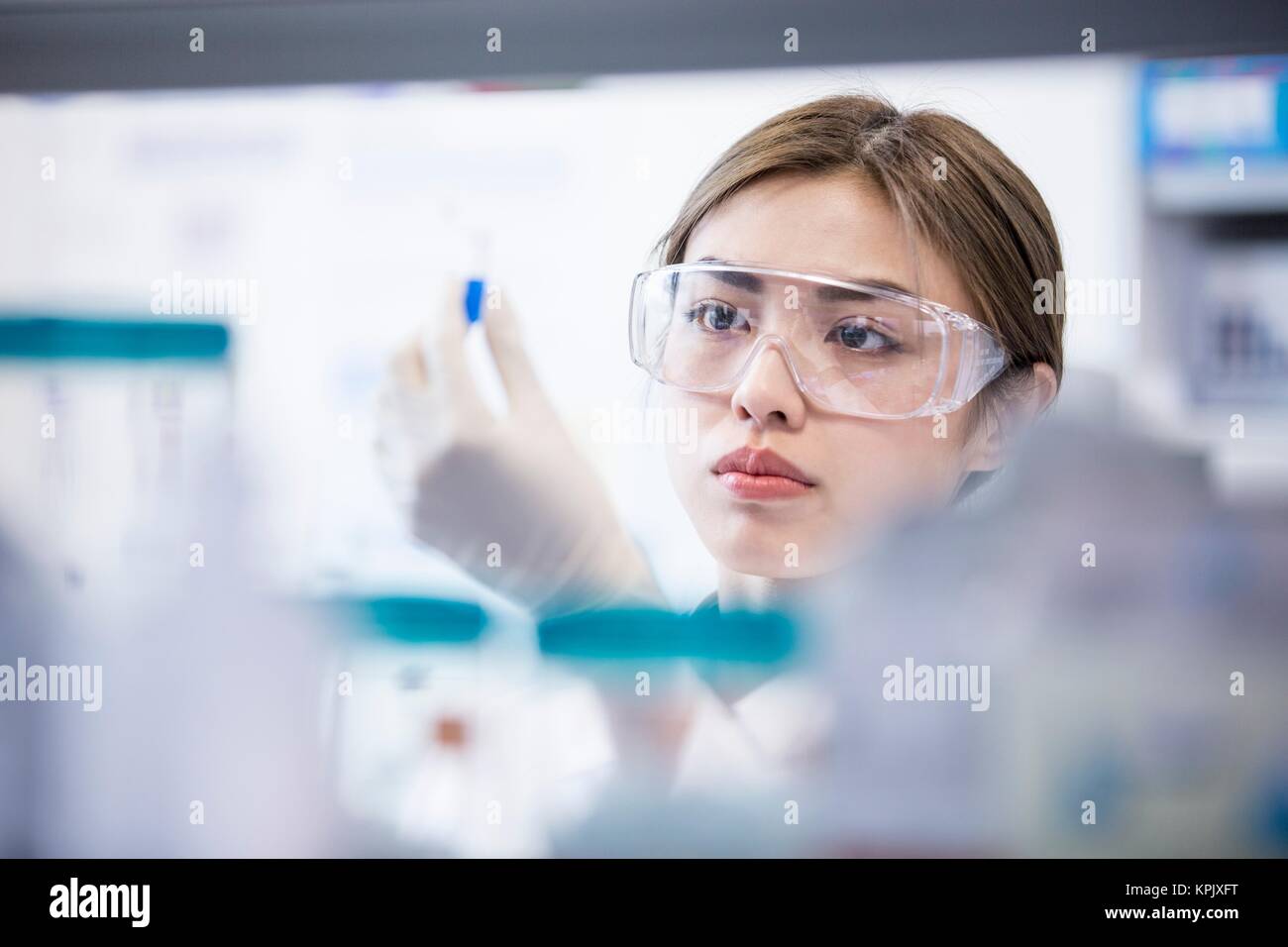 Female laboratory assistant wearing safety goggles. Stock Photo