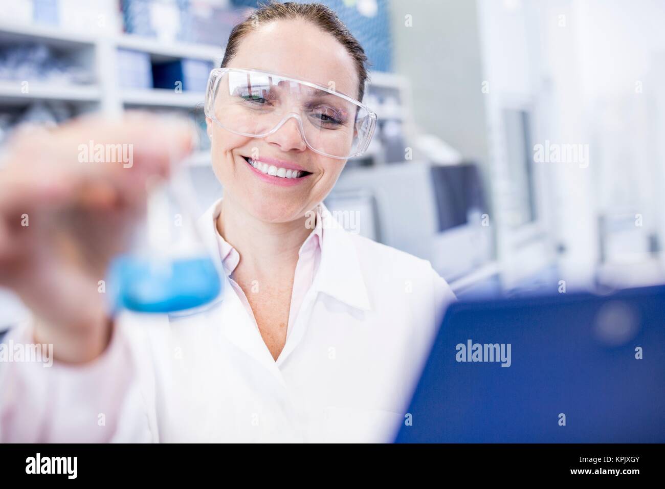 Female laboratory assistant holding chemical flask. Stock Photo