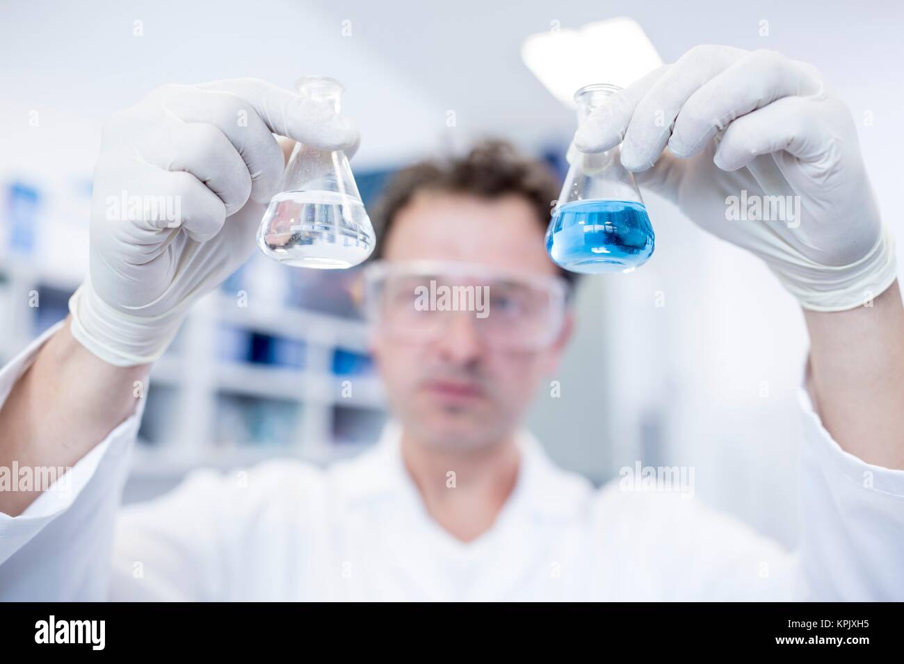 Male laboratory assistant holding two chemical flasks. Stock Photo