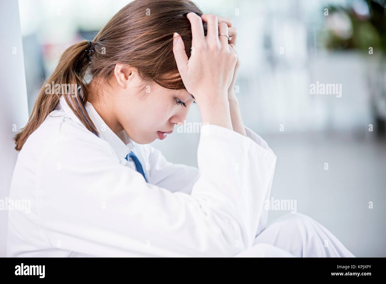 Young female medical student with head in hands. Stock Photo