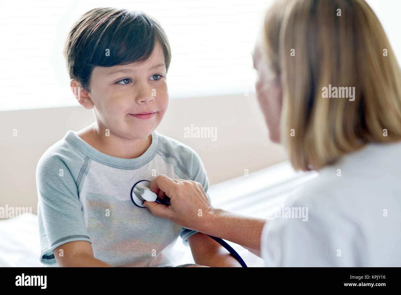 Young boy looking towards nurse with stethoscope. Stock Photo