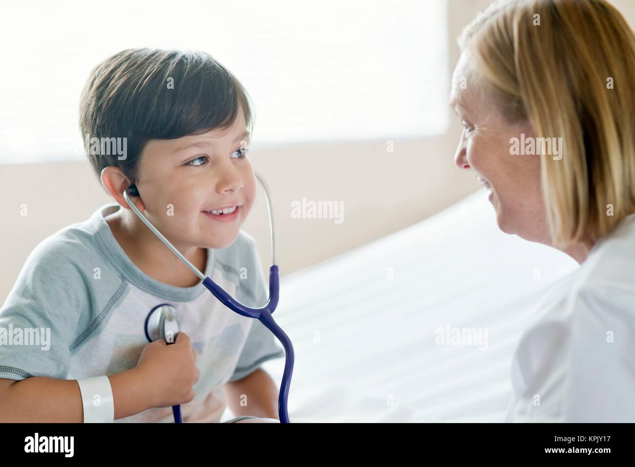Young boy smiling towards nurse wearing stethoscope. Stock Photo