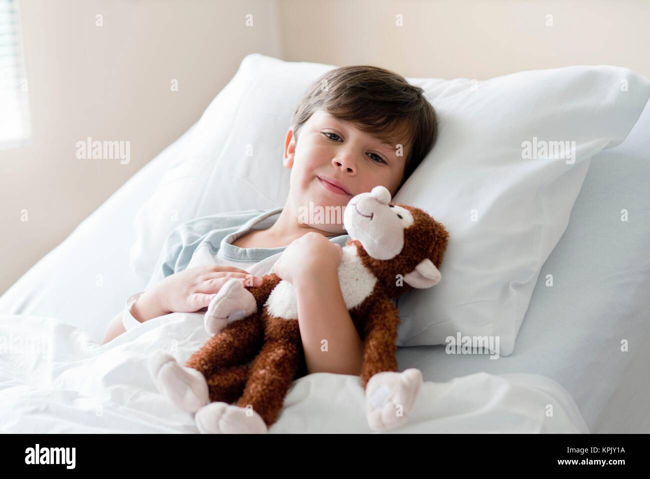 Young boy in hospital bed with teddy bear. Stock Photo