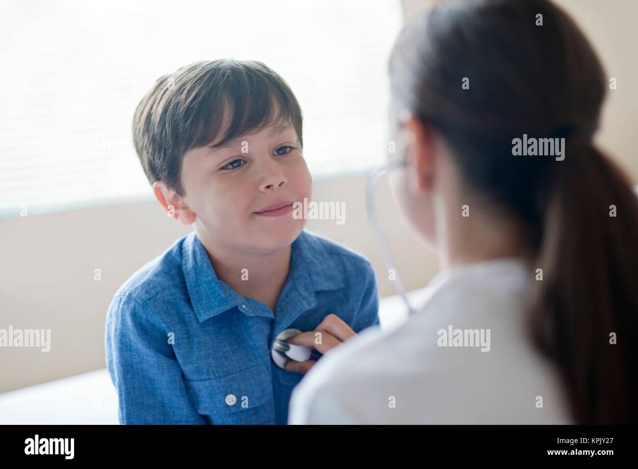 Young boy looking toward nurse using stethoscope. Stock Photo