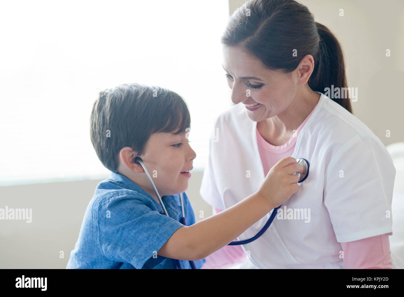 Young boy and nurse playing with stethoscope. Stock Photo