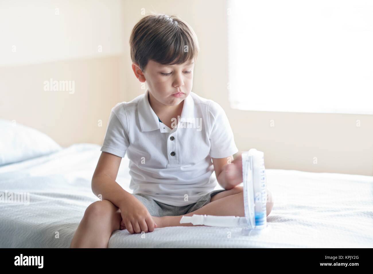 Young boy sitting on hospital bed with breathing equipment. Stock Photo