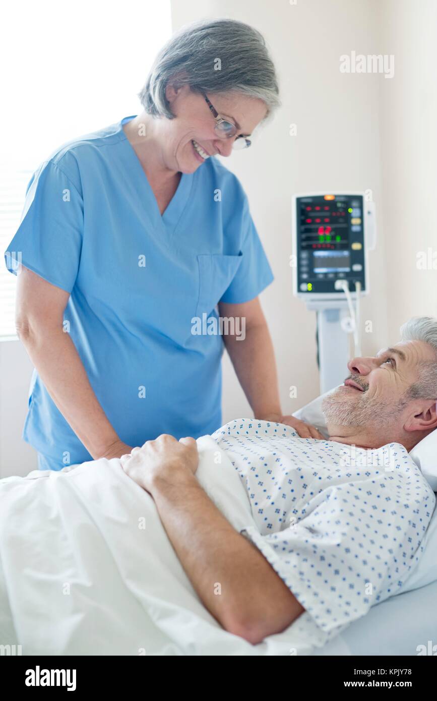 Female nurse talking to male patient in hospital bed Stock Photo - Alamy