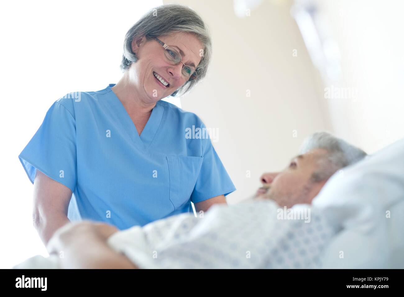 Female nurse talking to male patient in hospital bed Stock Photo - Alamy