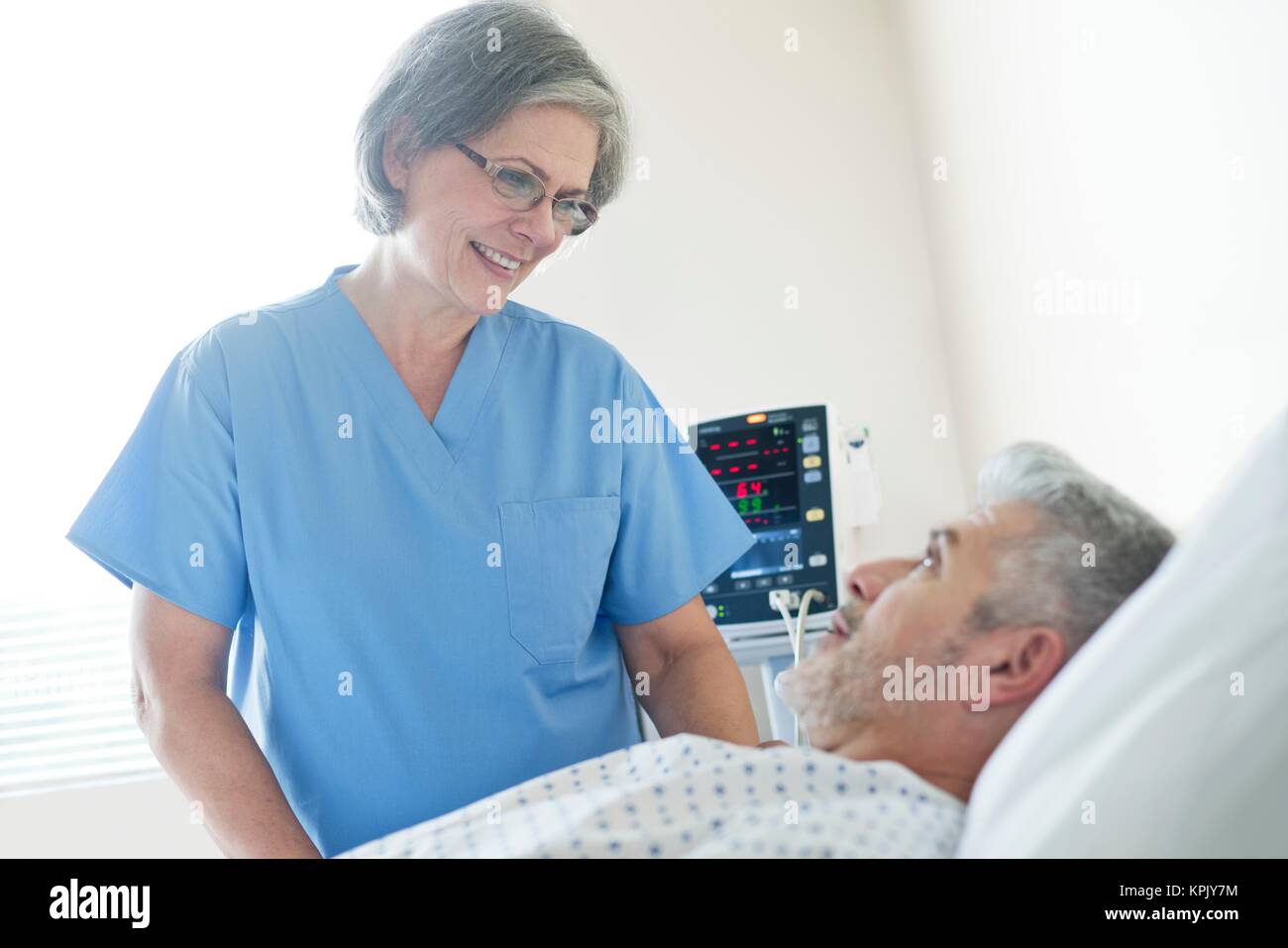Female nurse talking to male patient in hospital bed Stock Photo - Alamy