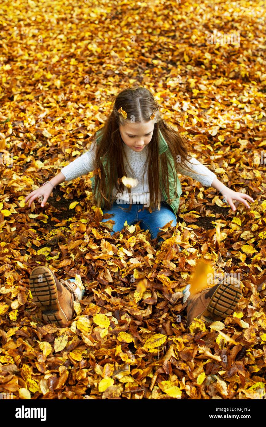 Girl sitting in a pile of Autumn leaves Stock Photo - Alamy