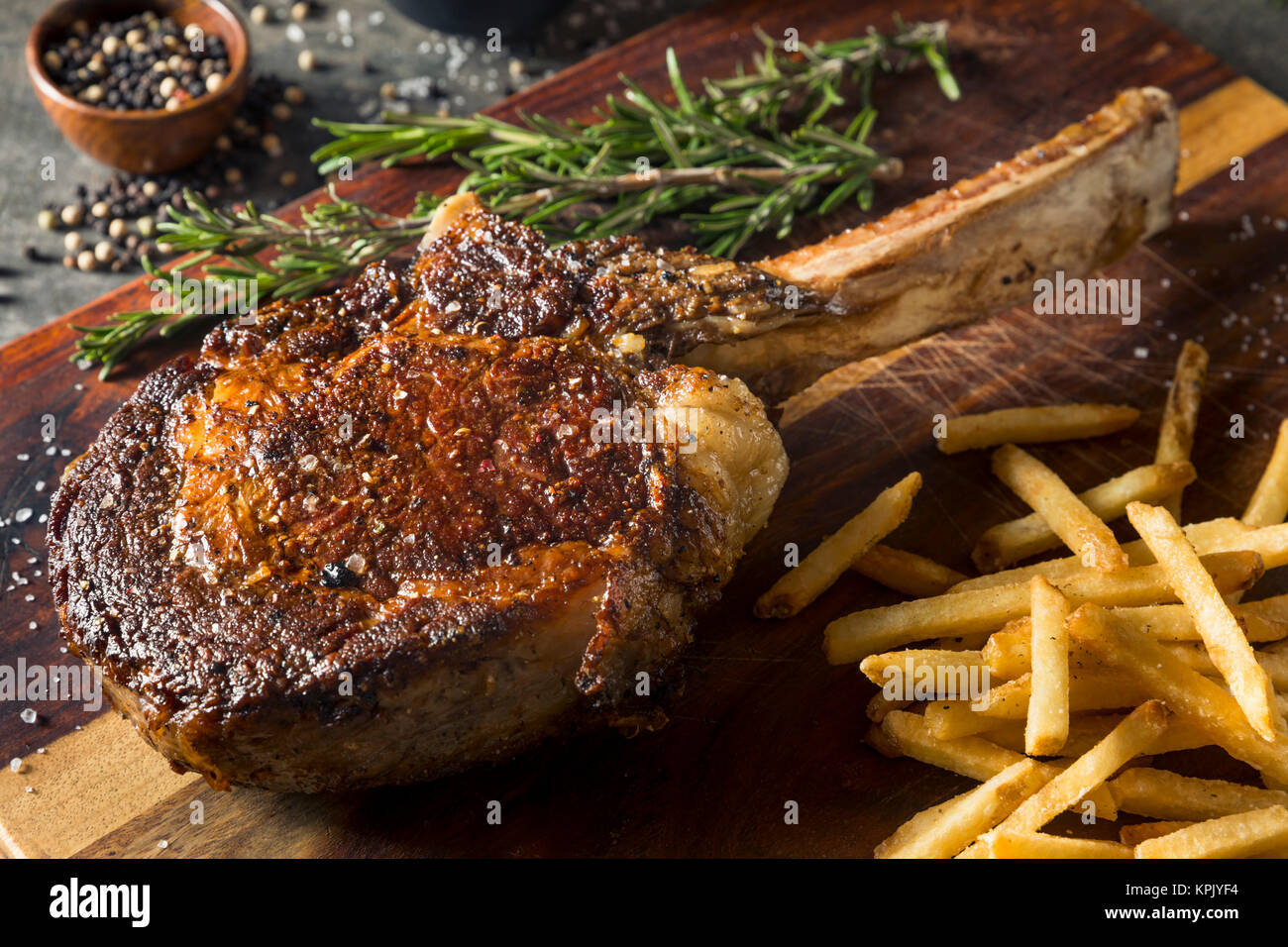 Cooked Grass Fed Tomahawk Steaks with Fries and Rosemary Stock Photo