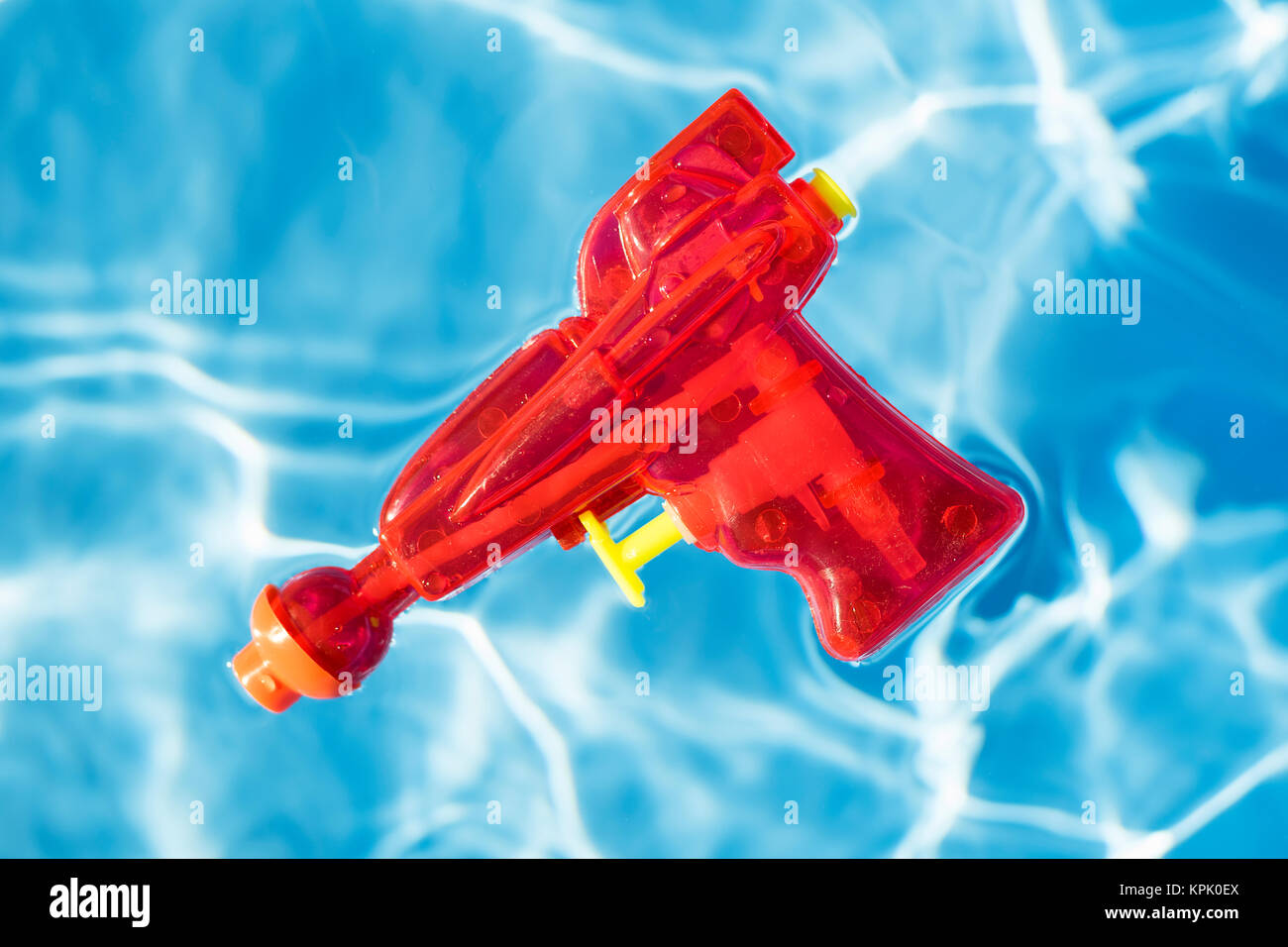 Red squirt gun floating in water. Stock Photo