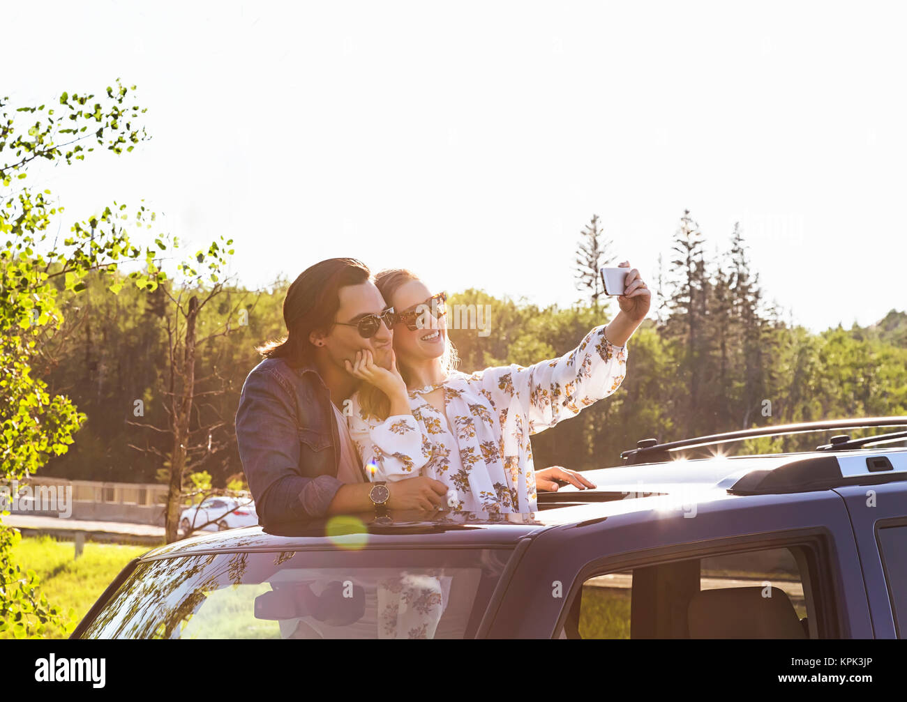 Young couple taking selfies with a cell phone in their vehicle; Edmonton, Alberta, Canada Stock Photo