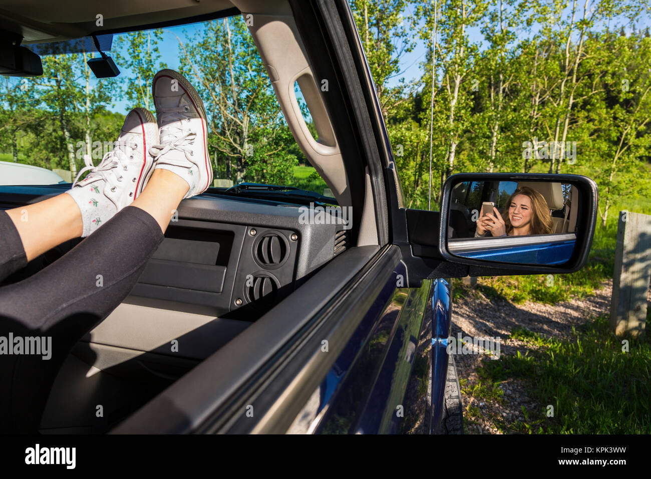 Young woman using her cell phone in a passenger seat in a vehicle; Edmonton, Alberta, Canada