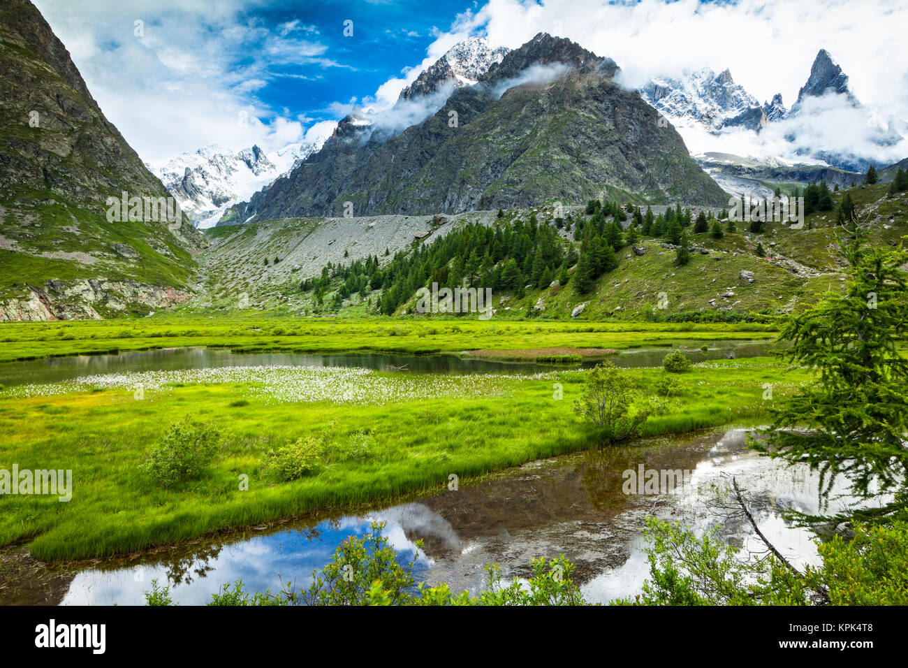 Lac de Combal and green meadow in Val Veni with mountains in the background, Alps; Aosta Valley, Italy Stock Photo