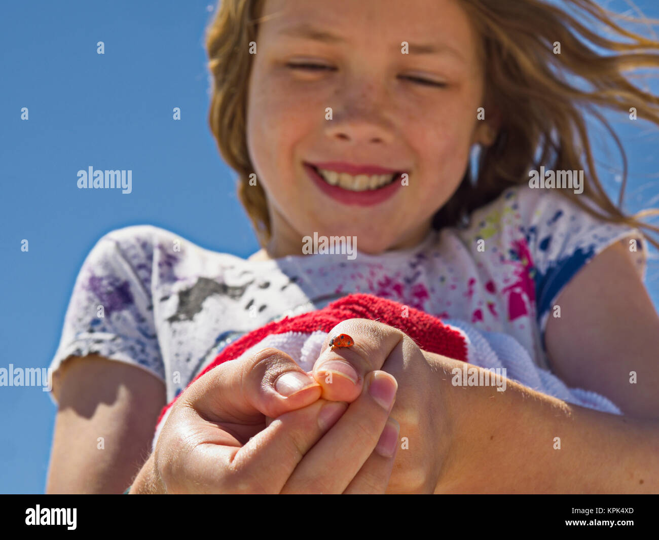 A young girl shows off a ladybug (Coccinellidae) she caught and is holding on her thumb; Destin, Florida, United States of America Stock Photo