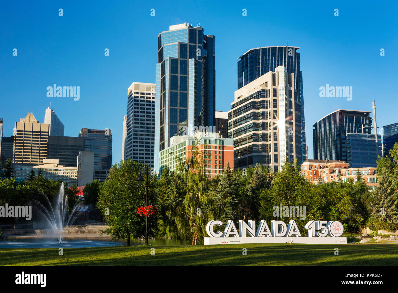 Canada 150 signage in city park with Calgary building towers in