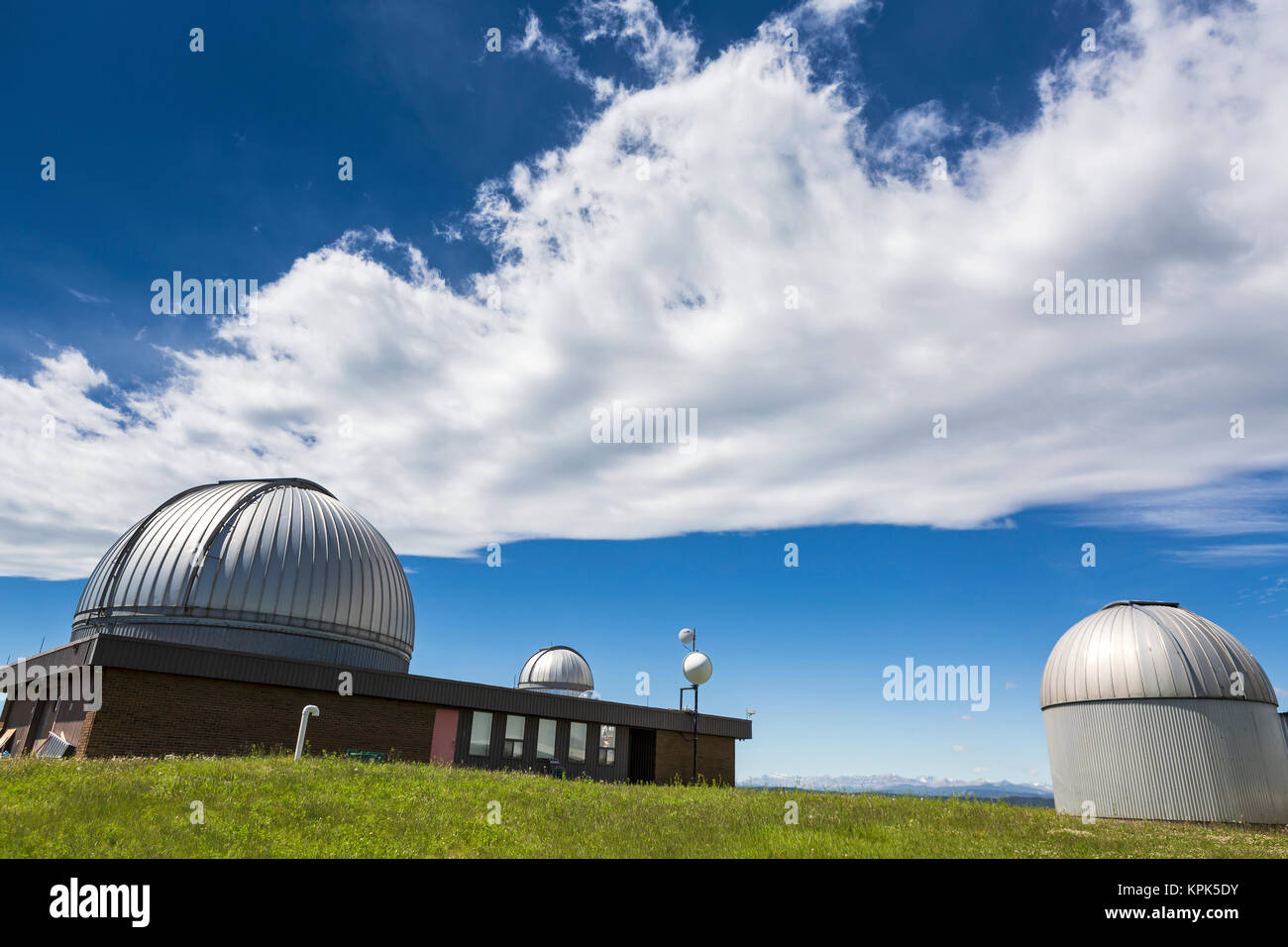 Domes of Astrophysical Observatory with dramatic clouds and blue sky, Southwest of Calgary; Alberta, Canada Stock Photo