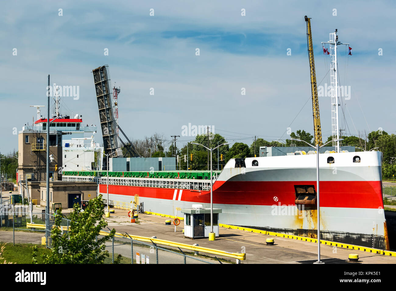 Large laker ship going through canal locks with lifted bridge in the background; Port Colborne, Ontario, Canada Stock Photo
