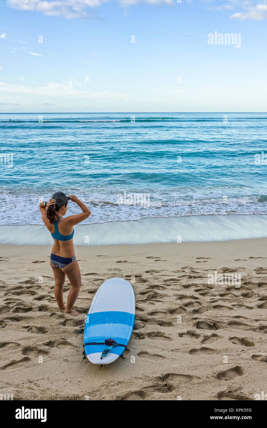 Young female surfer prepares on the beach to go out to the water; Honolulu, Oahu, Hawaii, United States of America Stock Photo