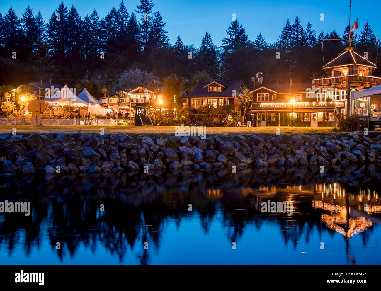 The heritage site tourist attraction Union Steamship Building in Snug Cove, Bowen Island is lit up at night welcoming tourists to the restaurant, s... Stock Photo